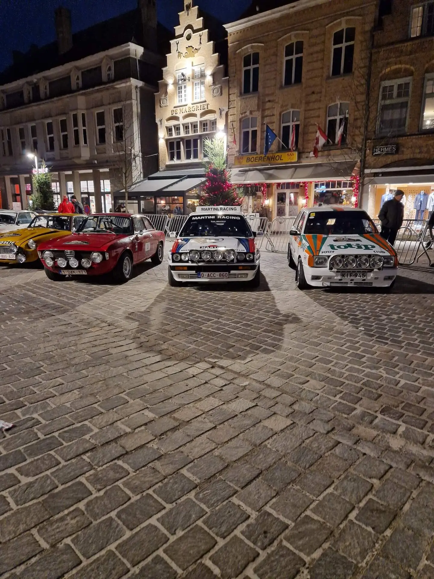 Klassieke rallywagens geparkeerd op een avondplein